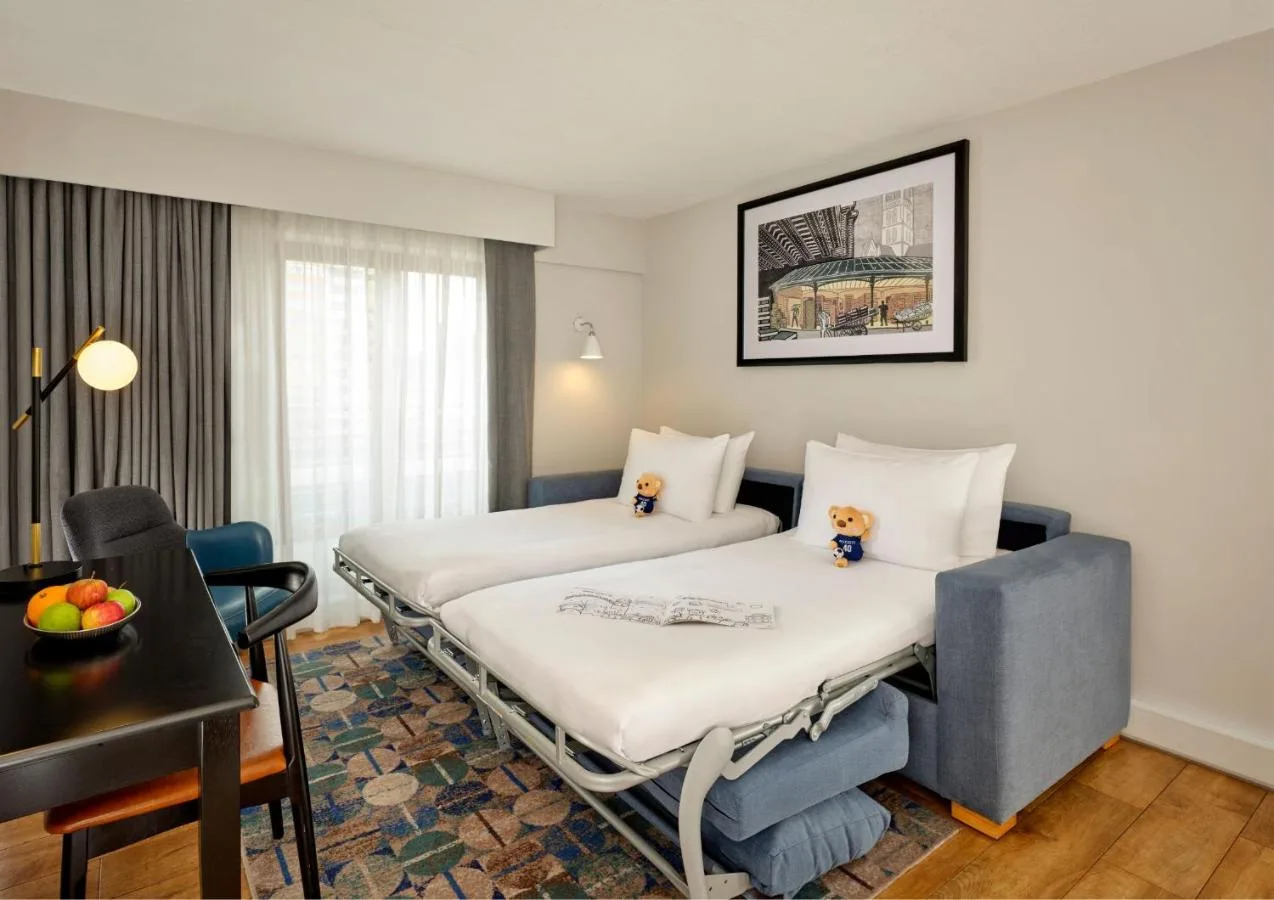 a hotel room with two beds and a table at Citadines Barbican London in London
