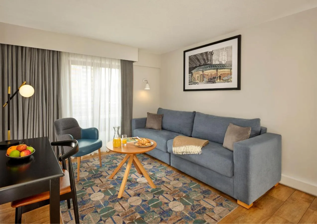 a living room with a blue couch and a table at Citadines Barbican London in London