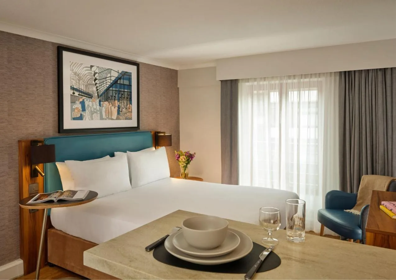 a hotel room with a bed and a table with a plate on it at Citadines Barbican London in London